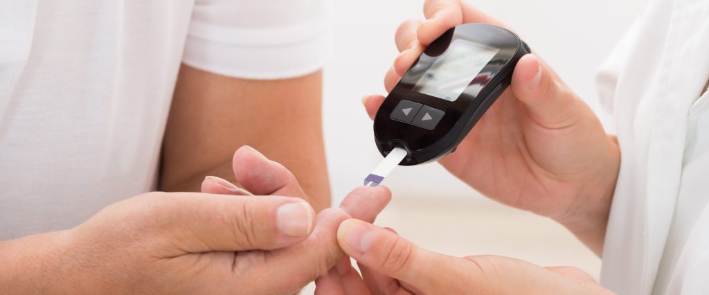 Doctor Using Glucometer On Patient's Finger